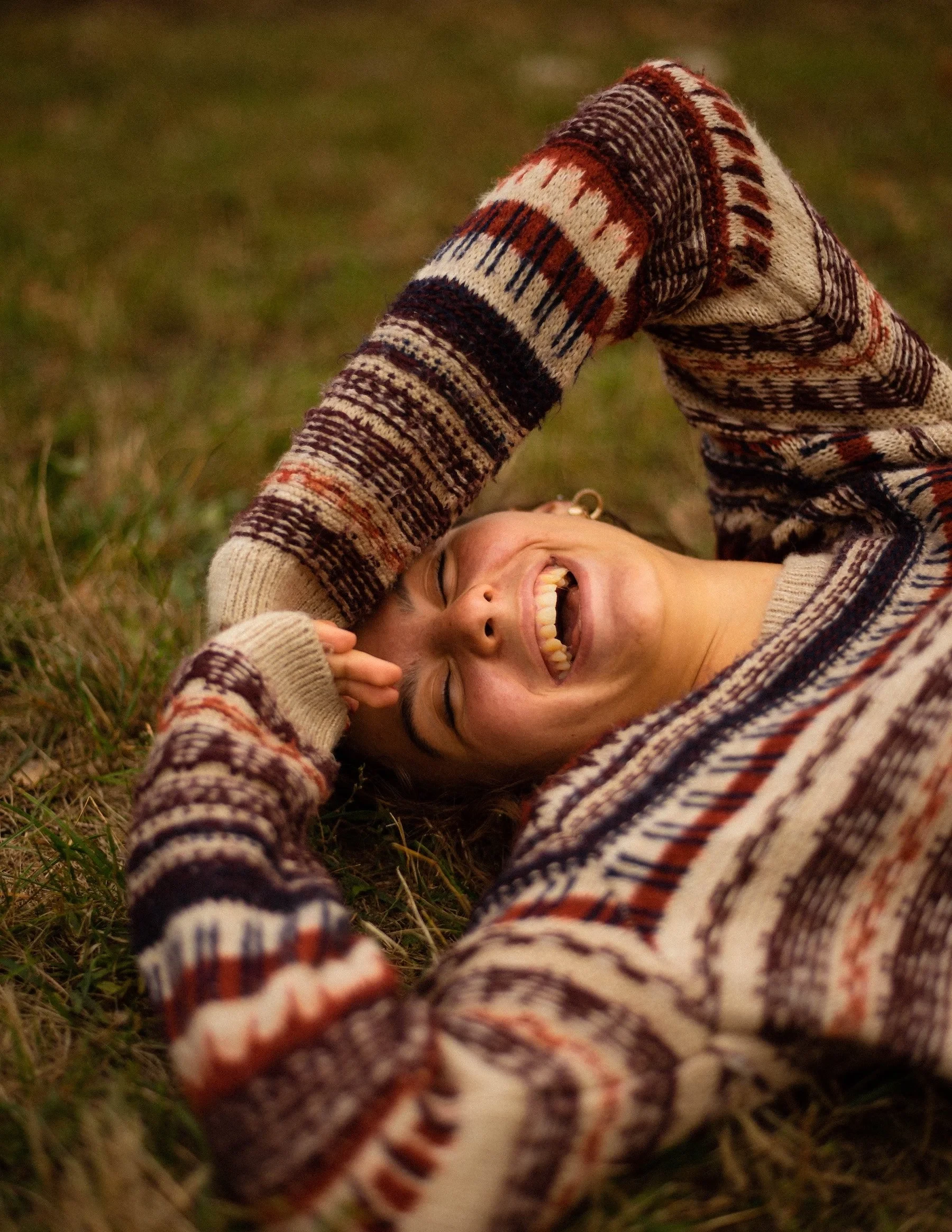 Girl laughing on her back on grass